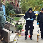 Deux policiers sur le trottoir près de cônes marquant des indices.
