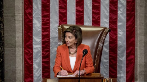 Nancy Pelosi assise dans son fauteuil officiel devant les élus américains.