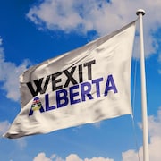 Un drapeau représentant le wexit albertain flotte dans un ciel bleu avec quelques nuages. 