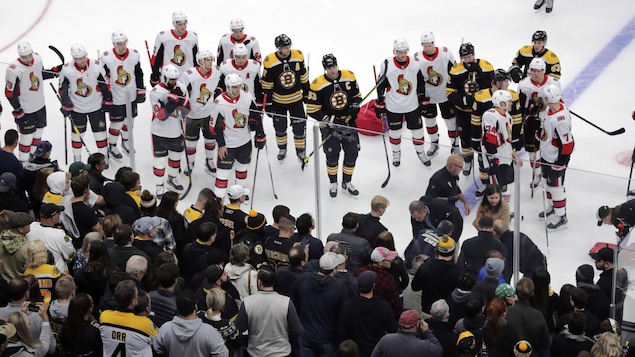 Des joueurs des Bruins et des Sénateurs sont sur la glace au moment où Scott Sabourin est emmené sur une civière. 