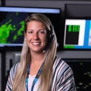 Une femme souriante dans un centre de contrôle aérien. 