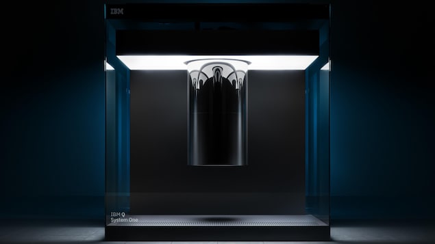 Une photo montrant l'ordinateur quantique Q System One d'IBM, un grand cube de verre contenant un cylindre chromé suspendu.