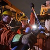Deux travailleurs d'Hydro-Québec réparent un poteau endommagé par les intempéries, à l'aube.