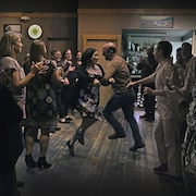 Un homme et une femme au milieu d'un groupe qui font des danses traditionnelles dans une taverne.