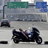 Un homme est couché sur sa moto, au milieu d'une autoroute à plusieurs voies.