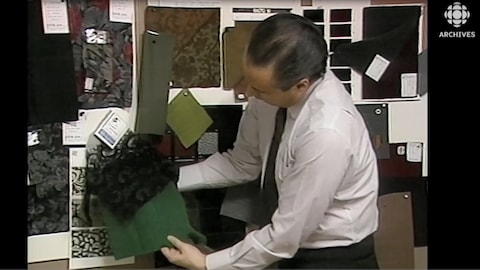Le couturier Jean-Claude Poitras regarde des tissus dans son atelier.