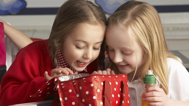 Deux fillettes regardent l'intérieur d'une boîte à lunch