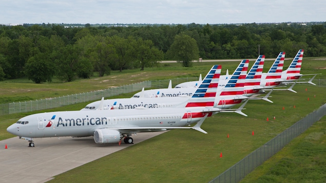 Cinq avions affichant le logo d'American Airlines sont stationnés en rangée.