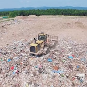 Un camion ensevelit des déchets sous la terre.
