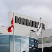 Des drapeaux aux couleurs de Bombardier, du Québec et du Canada.