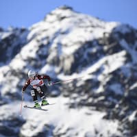 Le skieuse canadienne dans les airs pendant une épreuve de ski cross. En arrière-plan, une montagne enneigée. 