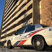 Une autopatrouille de la police de Toronto stationné devant une grand tour d'habitation, marquée par l'incendie.