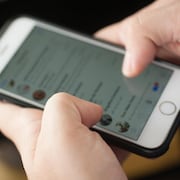 Un homme tape sur l'écran de son téléphone intelligent dans une application de messagerie.