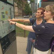 Deux femmes consultent une carte touristique.