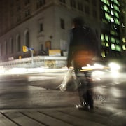 Des piétons traversent la rue le soir à une intersection du centre-ville de Toronto.