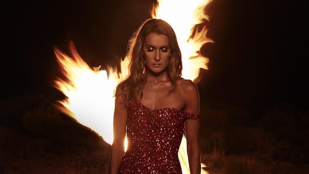 Couverture de l'album « Courage », qui représente Céline Dion, en robe longue rouge, devant un feu