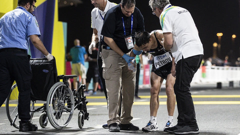 Un concurrent reçoit l'aide du personnel médical dans l'aire d'arrivée du marathon des Championnats du monde de Doha au Qatar.