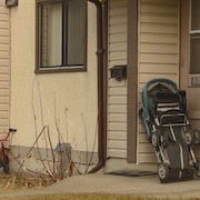 Des maisons en rangées. On voir une poussette repliée et des vélos d'enfant près des murs.