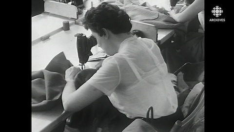 Une couturière courbée sur sa machine à coudre dans une manufacture.