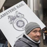 Un employé du CN porte une pancarte à l'extérieur du siège social du CN à Montréal, le mardi 26 novembre 2019. 