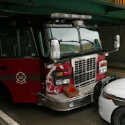 Un camion de pompier dont les phares du côté passager sont endommagés fait face à une voiture de police.