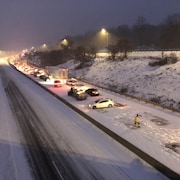 Des véhicules sont immobilisés sur une autoroute enneigée.