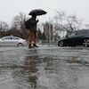 Un homme traverse une rue inondée d'eau de pluie.