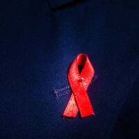Un ruban rouge, symbole de la lutte contre le sida et le VIH, épinglé sur une veste.