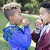 Deux enfants croquent dans une pomme. 