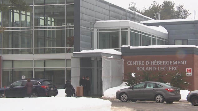 Un édifice avec l'inscription « Centre d'hébergement Roland-Leclerc » affichée sur un mur extérieur. En hiver. Des automobiles sont stationnées devant.
