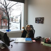 La nouvelle députée fédérale de Trois-Rivières, Louise Charbonneau, assise derrière son bureau, avec un écriteau où son nom est inscrit. 