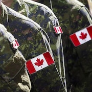 Des soldats canadiens en uniformes de combat avec le drapeau canadien sur le bras.