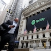 Un piéton passe devant la façade de la Bourse de New York aux couleurs de l'entreprise Spotify.