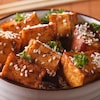 Des carrés de tofu cuit avec des graines de sésames.