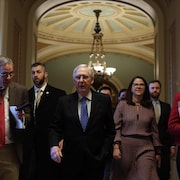 Mitch McConnell marche dans les corridors du Sénat entouré de ses collaborateurs.