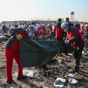 Des secouristes placent les corps des victimes dans des sacs de plastique.
