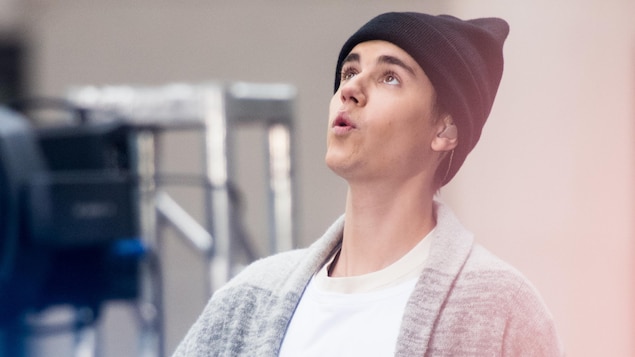 Justin Bieber porte un bonnet et regarde vers le ciel. 