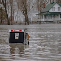 Une pompe à essence émerge de l'eau près du rivage inondé de la rivière des Outaouais, à Saint-André d'Argenteuil.