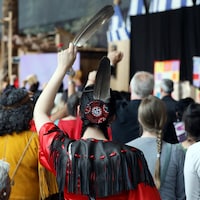 Une femme de dos tient une plume d'aigle pendant la cérémonie de fermeture de l'Enquête nationale sur les femmes et les filles autochtones disparues et assassinées.