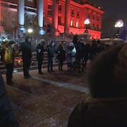 Des gens se tiennent par la main devant l'assemblée législative de l'Alberta.