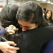 Deux jeunes femmes pleurent dans les bras l'une de l'autre.