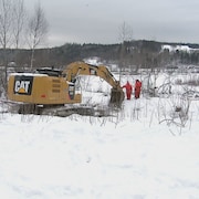 Des travailleurs et une pelle mécanique sur le bord de la rivière Chaudière pour retirer l'estacade de Beauceville.