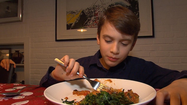 Un enfant mange son repas avec une fourchette.