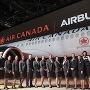 Des employés d'Air Canada posent devant un avion A220-300 dans un hangar à Montréal.
