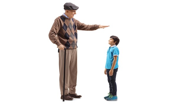Un homme âgé mesure la taille d'un enfant à l'aide de sa main.