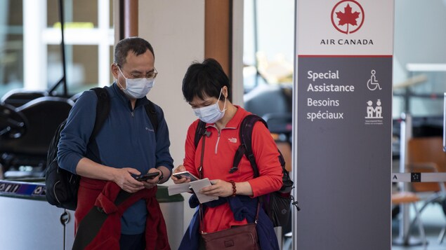 Des passagers vérifient leurs billets au kiosque d'Air Canada à l'aéroport international de Vancouver (YVR). 