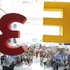 Une photo montrant une foule rassemblée dans le Centre des congrès de Los Angeles. En avant-plan, on peut voir le logo de l'E3 suspendu en l'air par des câbles.