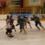 Des joueurs se disputent la rondelle sur la glace autour d'un arbitre.