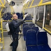Un homme nettoie des sangles dans un autobus.