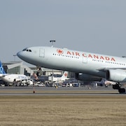Un avion d'Air Canada passe devant un autre d'Air Transat à l'aéroport Montréal-Trudeau.